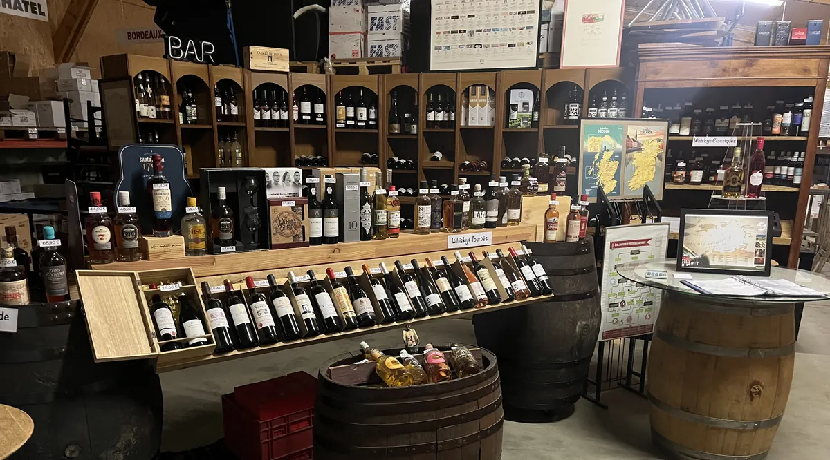Les rayons de la boutique : vins, whiskies et rhums présentés sur des fûts