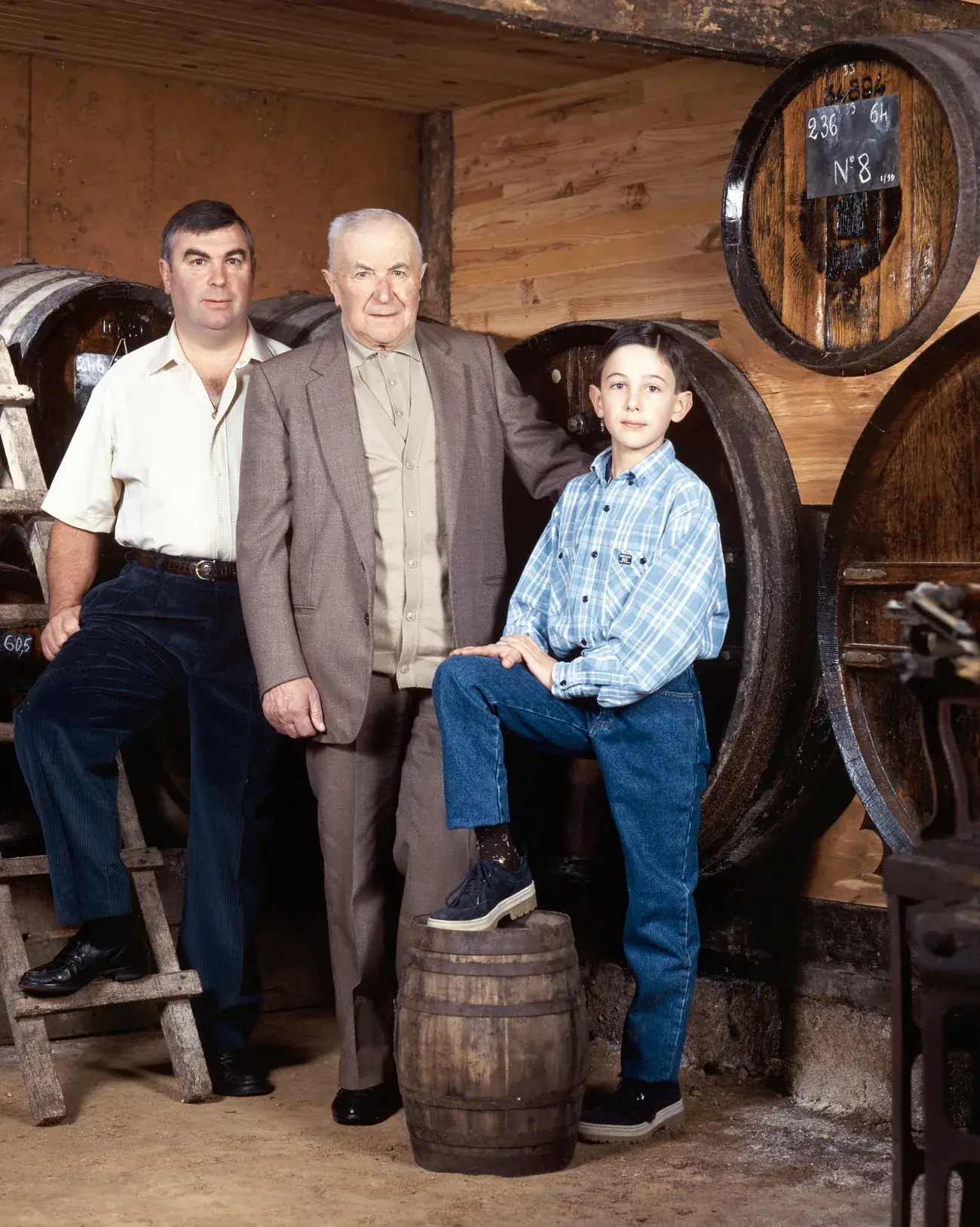 Trois générations de la famille Chatel dans le chai de vieillissement : Jean-Marie, Marcel et Constant enfant